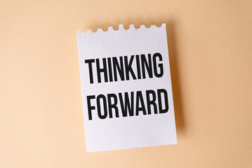 Thinking Forward text on white sticky note on yellow background.