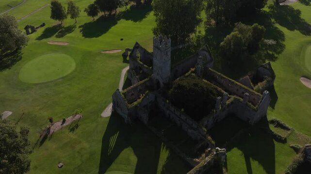 Franciscan Friary, Adare, County Limerick, Ireland, September 2024. Drone orbits counter clockwise rising above the historic Chistian ruin covered in moss and ivy in middle of a golf course.