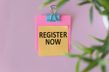 Register Now written on a paper with office tools and keyboard on the pink background