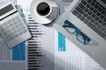 Office desktop with financial charts and laptop