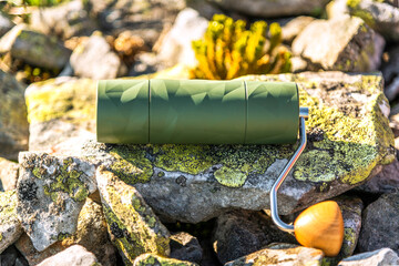Close-up of a green coffee grinder in rocky background. Composition with lot of copy space