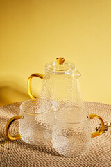 Glass set of teapot and mug on a yellow background