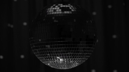 Shimmering silver disco ball spins in dimly lit room, casting vibrant reflections on the walls