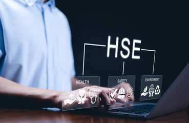 HSE - Health, Safety, and Environment. Businessman using laptop with icons representing health, safety, and environmental care, workplace safety, health management, and environmental responsibility.