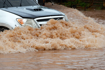 Muddy rain from a heavy rainy season flooded main roads connecting the district, making it difficult for cars to pass through and causing engine failures, in motion, car insurance concept.