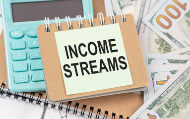 income streams text on a notebook in the hands of a businessman on the background