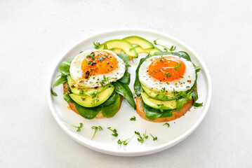 Fried eggs, avocado and greens on bread