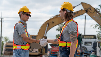 Caucasian white civil engineer, architect, or construction worker is wearing a safety suit while inspecting building construction on site and verifying blueprints or drawing plans.