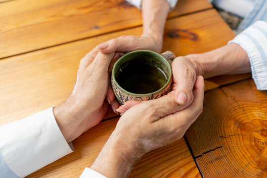 close up hands elderly people sitting at the table woman with a cup of tea happy old age elderly couple pleasant memories leisure time in old age warm feelings support in old age difficult times