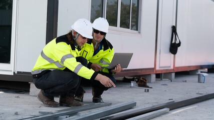 Caucasian white civil engineer, architect, or construction worker is wearing a safety suit while inspecting building construction on site and verifying blueprints or drawing plans.