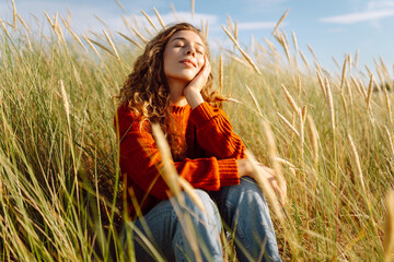 Happy woman enjoying nature outdoors in tall grass. Flying hairs. Outdoor. Fashion style.