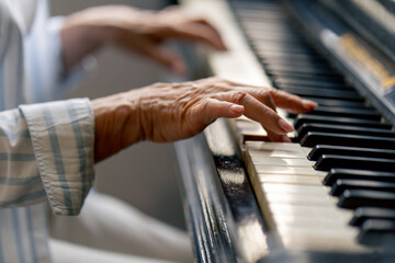 hands close up an elderly woman sits at the piano playing a melody learning new chords old age...