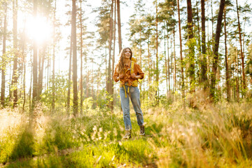 Female backpacker tourist looking up on trees and enjoying nature scenery. Active lifestyle. Hiking.