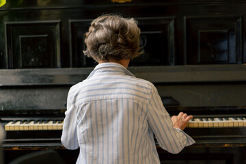 an elderly woman sits at the piano playing a melody learning new chords old age memories of an...