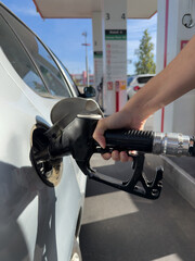 A person is filling up a car with gas at a gas station