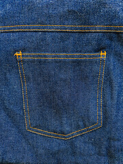 A fragment of denim clothing with a dark blue pocket.