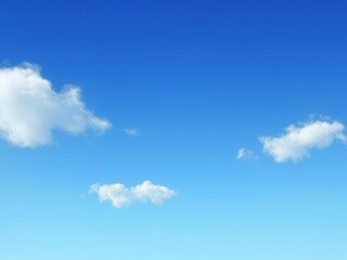 A few wispy gray clouds are scattered across the blue sky with a soft focus effect in an animated style, blue sky, gentle breeze