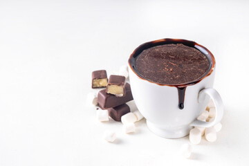 Marzipan hot chocolate, on table with ingredients, marshmallows and marzipan chocolates. Winter and Christmas comfort tasty hot cocoa drink in white cup