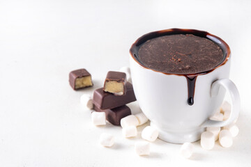 Marzipan hot chocolate, on table with ingredients, marshmallows and marzipan chocolates. Winter and Christmas comfort tasty hot cocoa drink in white cup