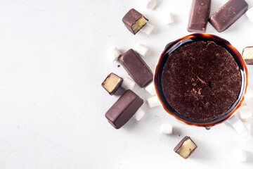 Marzipan hot chocolate, on table with ingredients, marshmallows and marzipan chocolates. Winter and Christmas comfort tasty hot cocoa drink in white cup