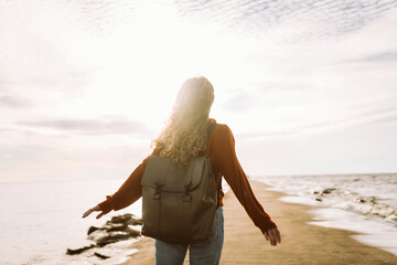 Portrait of woman enjoying a breezy day near a vibrant red lighthouse at sunset. Travel, weekend,...