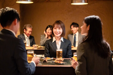 居酒屋で先輩社員とお酒を飲む新入社員