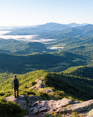 Naklejka premium Hiker Explores Stunning Mountain Landscape at Sunrise Overlooking Lush Valleys and Lakes