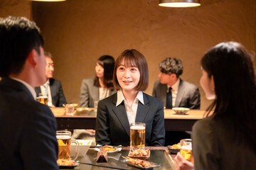 居酒屋で先輩社員とお酒を飲む新入社員