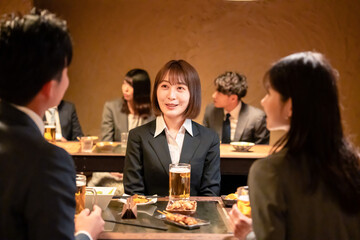 居酒屋で先輩社員とお酒を飲む新入社員