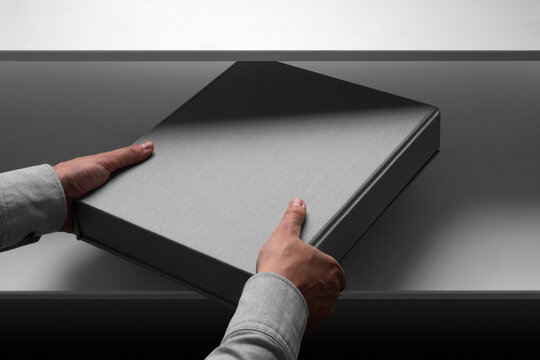A person places a modern binder box on a shelf. Isolated blank mockup surface to place your design. 