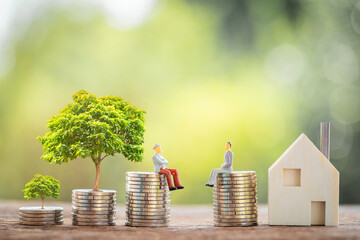 Two businessmen standing on the stack coins are negotiating for buy and sell or exchange purchase a home for compare and growing tree in the public park, Loan and investment for real estate concept.