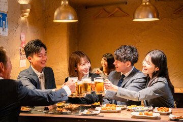 居酒屋で盛大に乾杯をするビジネスパーソン