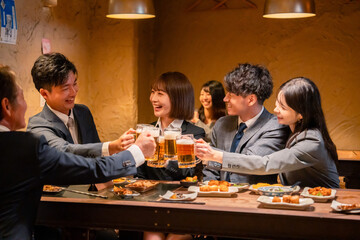 居酒屋で盛大に乾杯をするビジネスパーソン