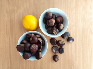 Obraz premium Yellow lemons and shiny brown chestnuts on the table