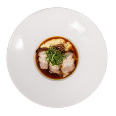 Tender slices of meat garnished with green herbs, served in a savory sauce on a white plate.