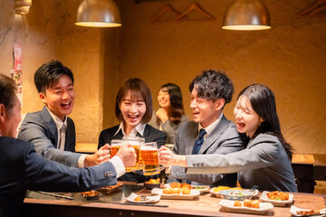 居酒屋で盛大に乾杯をするビジネスパーソン