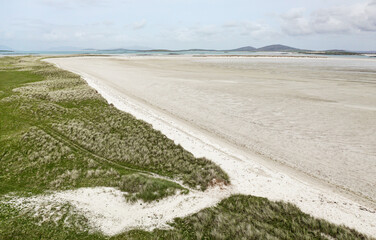 East from coastal machair sand dunes at Udal across the tidal sands of Traigh Ear at Grenitote on...