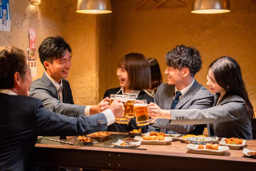 居酒屋で盛大に乾杯をするビジネスパーソン