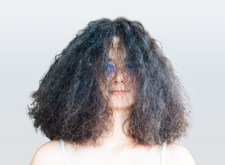 Portrait of a beautiful brunette wearing glasses with lush hair. Girl with tousled hair after blow drying smiling looking at camera.