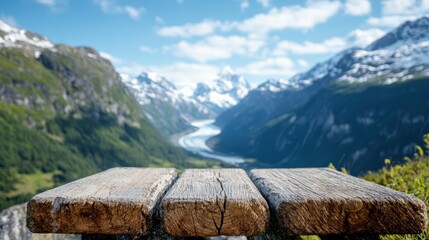 A rustic wooden bench sits in the foreground as a stunning mountain valley unfolds into the distance, merging the natural beauty of forests with snowy peaks and a winding river.