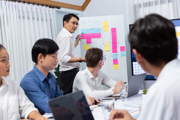 Group of diverse office worker employee take note and brainstorming on strategic business marketing planning using sticky note on white board in meeting room. Productive teamwork in workplace. Prudent