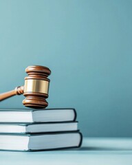 A wooden gavel sits on top of three books