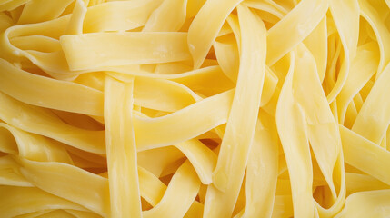 Fresh fettuccine pasta on plain background, showcasing its smooth texture and vibrant yellow color. Perfect for various delicious dishes