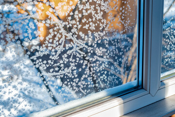 Frozen window with snowflakes. Ice pattern on winter glass. Frost on the window. Beautiful frost pattern on the window. Delicate frost pattern on the window glass