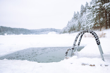 Ice swimming place. Bright winter day with a frosted ladder leading into a natural ice swimming...