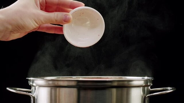 Professional chef adds paprika fragrant dry peppers to a pot of boiling food. Restaurant kitchen cooking, colorful spices, dropping spices.