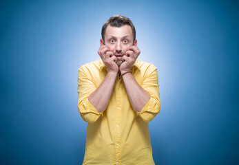 Mistake. Frightened young man stare to you over blue background, dresses in yellow shirt