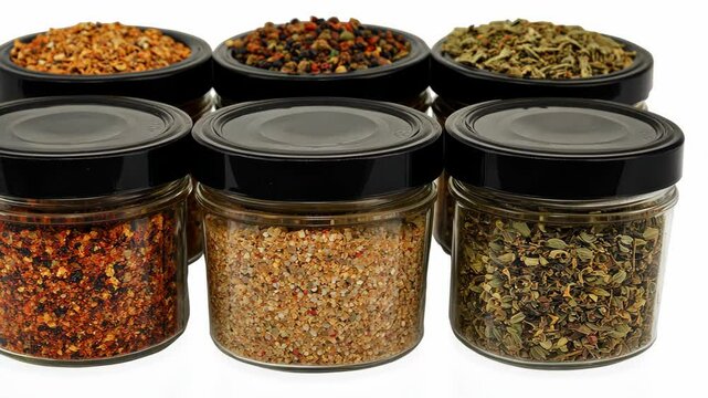 Various spice jars filled with colorful seasonings arranged neatly on a white background