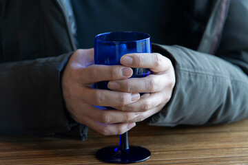 hands holding a blue glass cup
