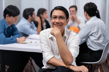 Engineer team leader portrait with diverse group of civil engineer and client working together on architectural project, reviewing construction plan and building blueprint at meeting table. Prudent